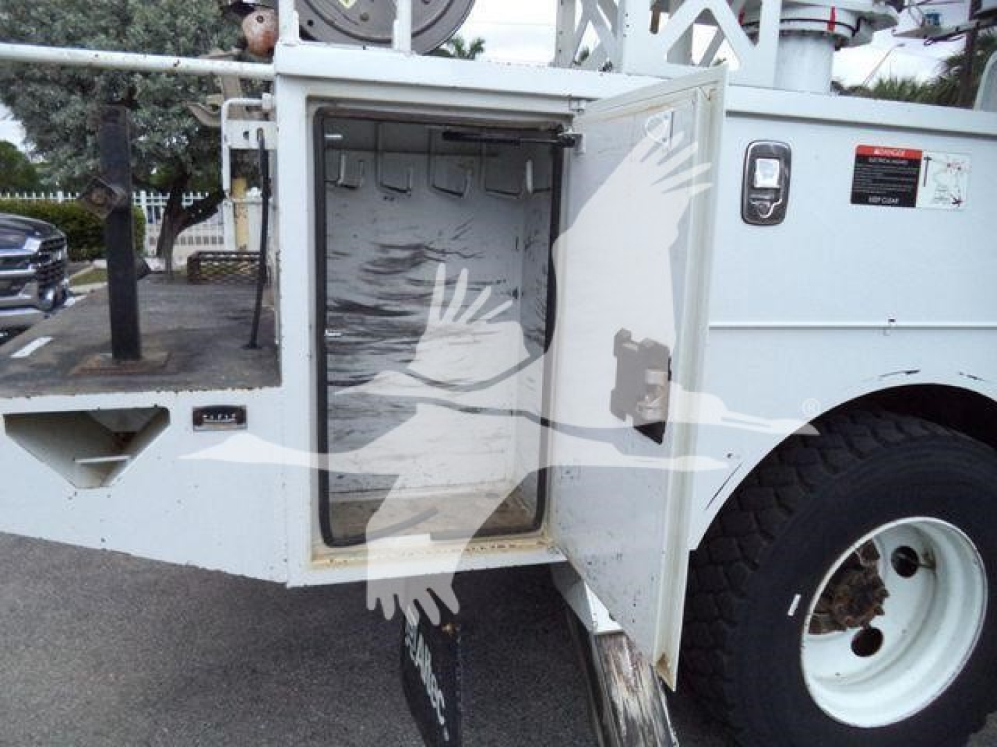 Altec L37M crane access door opening showing interior with storage space and control area, white equipment body with open compartment door.