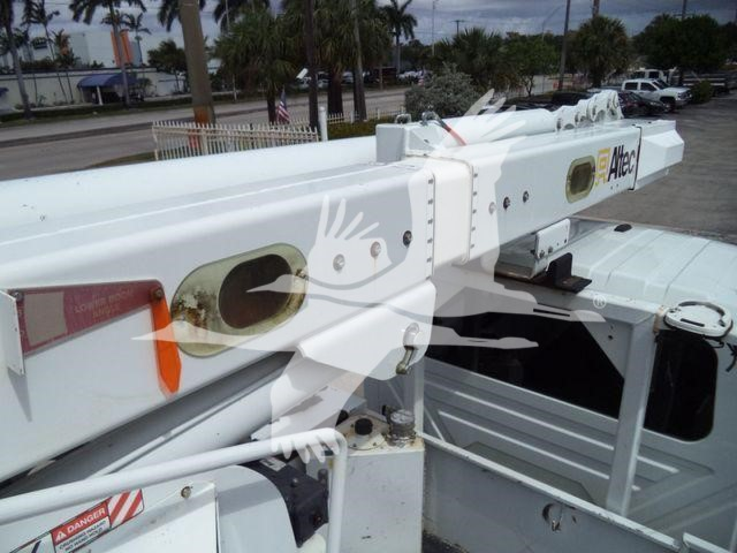 Altec L37M crane arm with white paint and orange warning markings, mounted on a utility truck. Visible labels include Altec branding and structural joints.