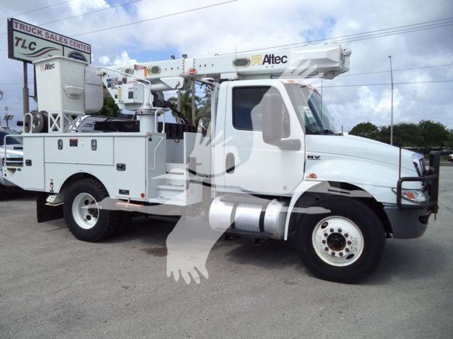 Altec L37M boom truck crane on white cab and chassis with utility compartments, crane boom retracted overhead, TLC dealer lot.
