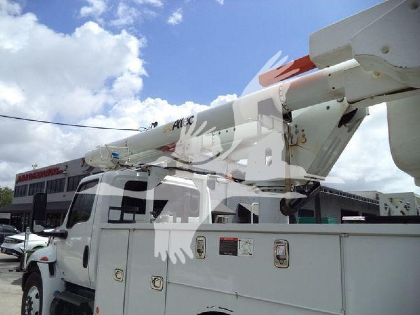Altec L37M crane mounted on a white utility truck, boom folded overhead, with control panels and storage compartments visible on the side.