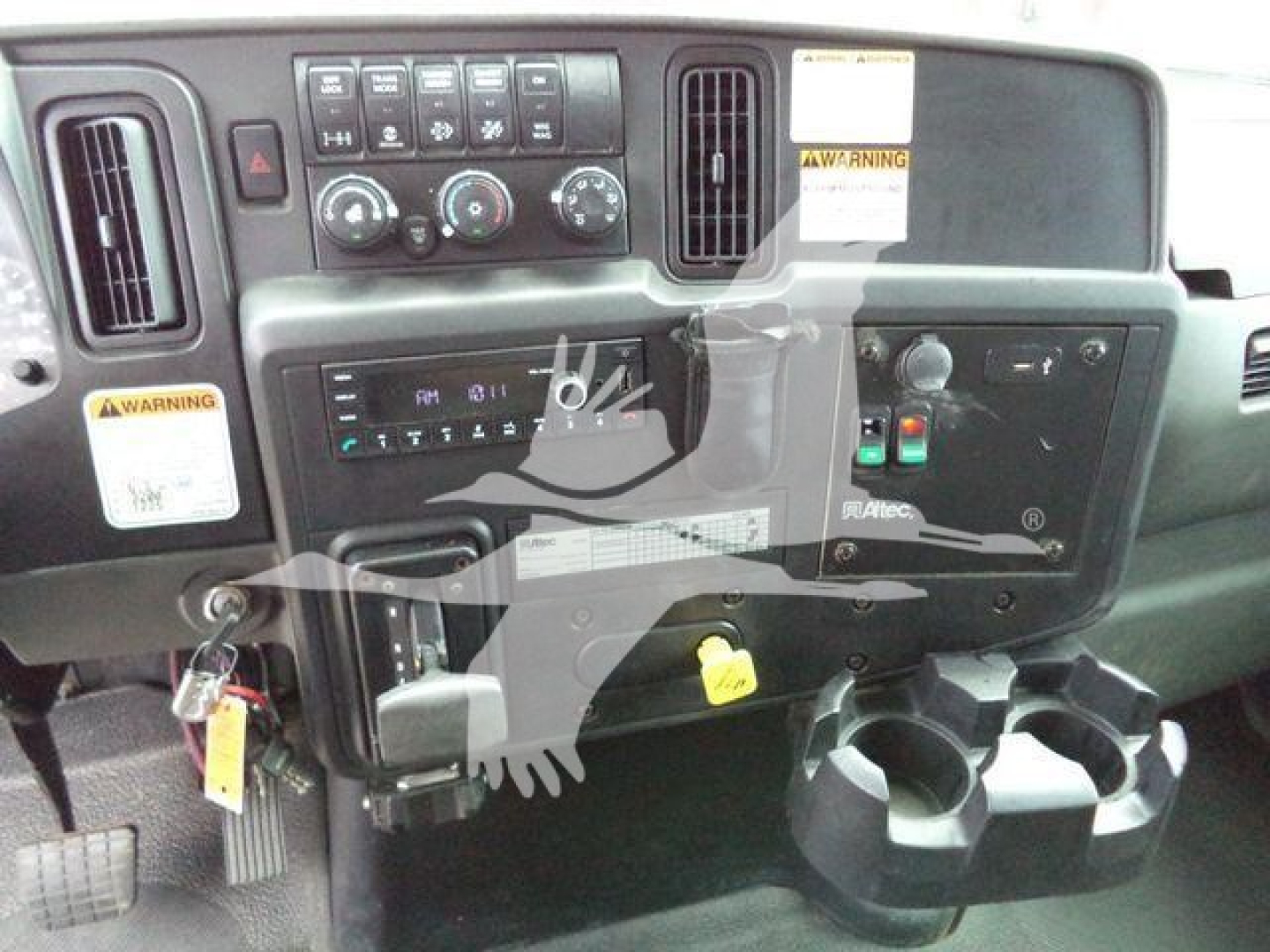 Altec L37M crane dashboard showing control panel, gauges, switches, and throttle/joystick area with cup holders in foreground