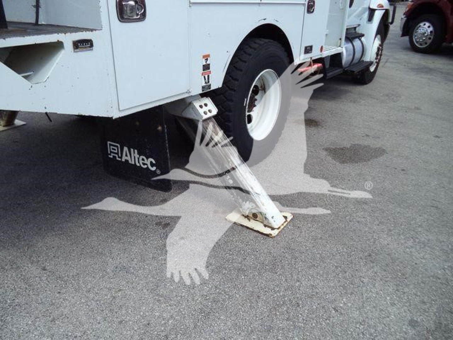 Altec L37M crane with stabilizer deployed on asphalt; visible Altec logo on mudflap and white body; rear wheel and hydraulic stabilizer leg in view.