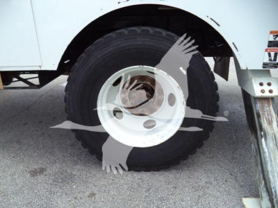 Altec L37M crane component: close-up of a white steel dual-wheel (hub) with black tire, part of undercarriage and stabilizer leg visible.