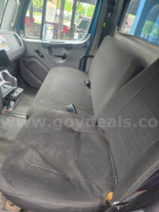 Truck cab interior with front and bench seats; steering column and dashboard visible; cloth seats with some wear.