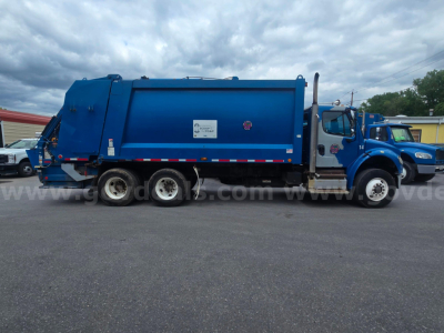 Freightliner M2 106 garbage truck side view showing large blue rear compactor body and cab with multiple axles.