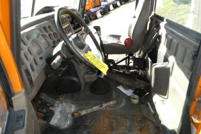 Cab interior of a 2004 Mack CX612 daycab showing steering wheel, dash, gears, and worn floor with pedals and controls visible.