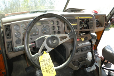 Mack CX612 truck interior driver’s seat and dashboard with steering wheel, gauges, and gear selector.