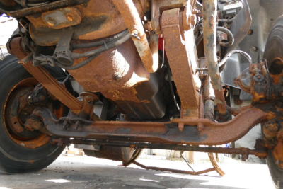 Underbelly view of a 2004 Mack CX612 conventional daycab showing rusted drivetrain components and suspension from below.
