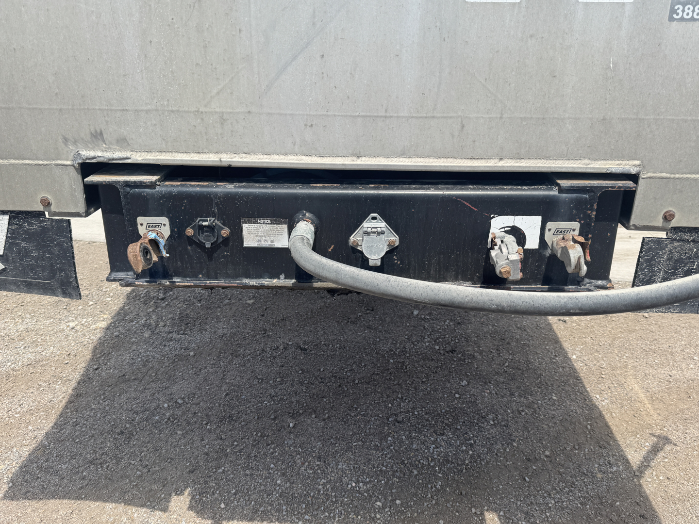 Trailer rear showing electrical connectors and hitch plate with labels near sockets