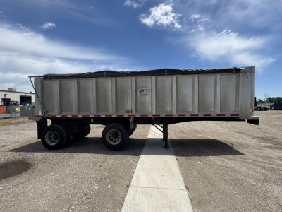 Dump trailer in side view showing East 2007 trailer with two axles and a raised tailgate. Brand label near center reads 'EAST' on silver container.