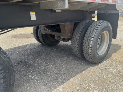 Trailer undercarriage showing dual rear tires and suspension components of a dump trailer.