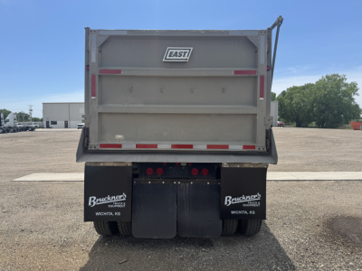 Trailer rear view showing East dump trailer with open gate and mud flaps branded Bruckner's Wichita KS; taillights and reflective strips visible.