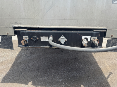 Trailer rear showing electrical connectors and hitch plate with labels near sockets