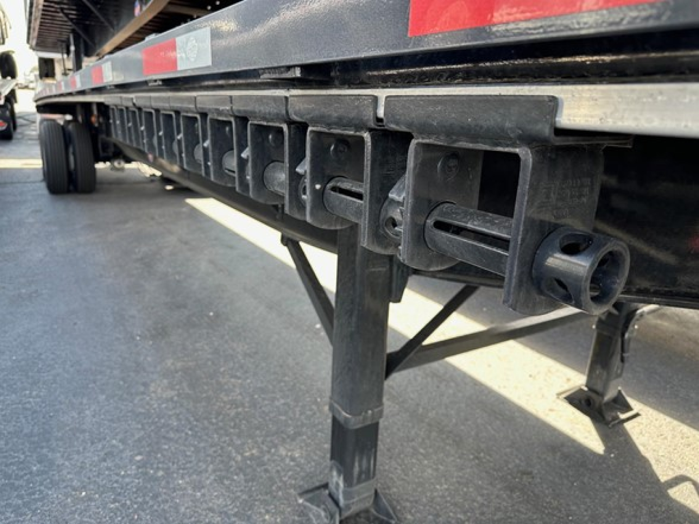 Flatbed trailer side with vertical stake pockets and latching mechanism visible, utility 4000S series marking and undercarriage support legs.