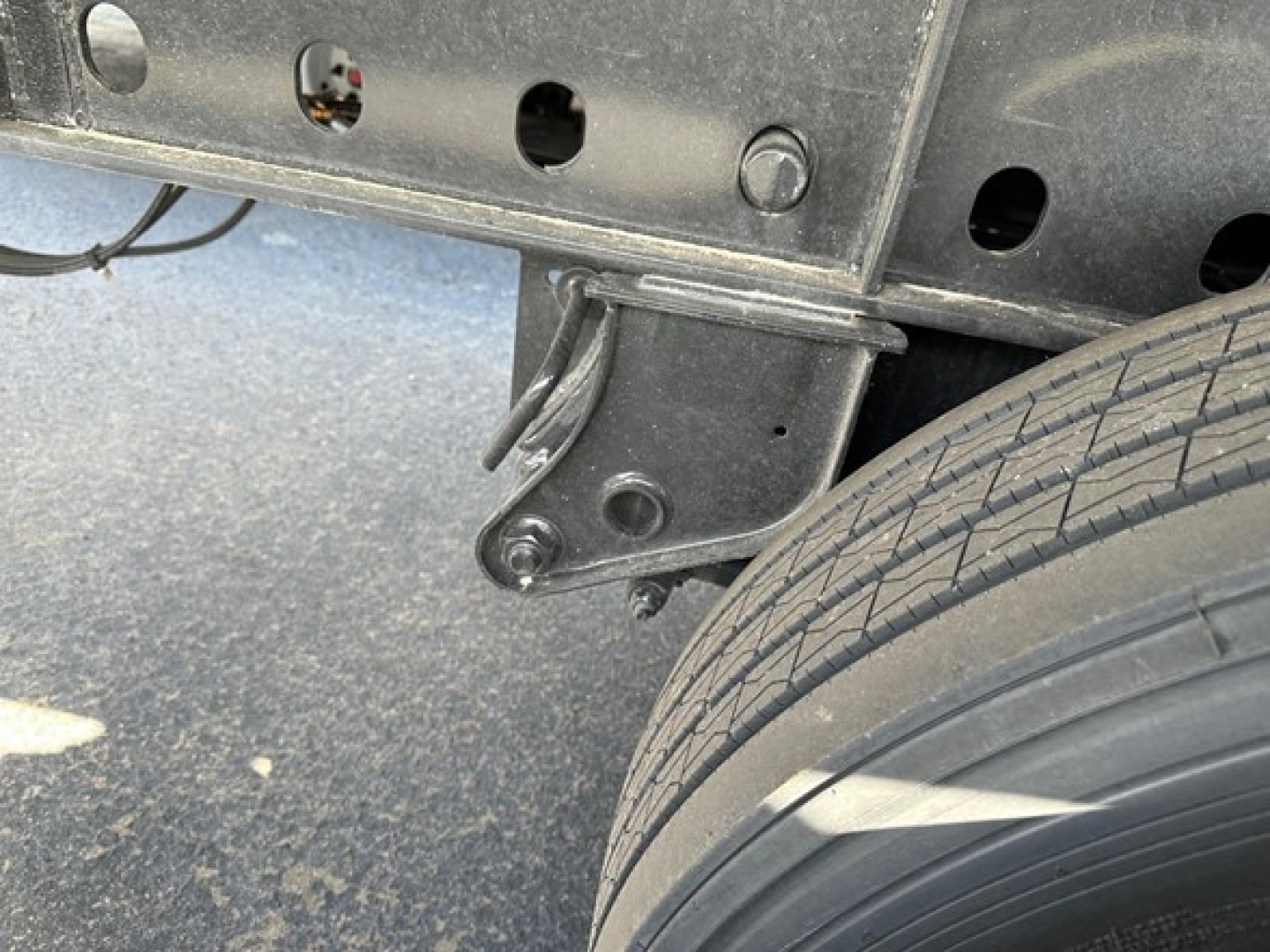 Trailer hitch plate with wiring and wheel well on a Utility 4000S flatbed trailer showing mounting bracket and wheel/tire tread.