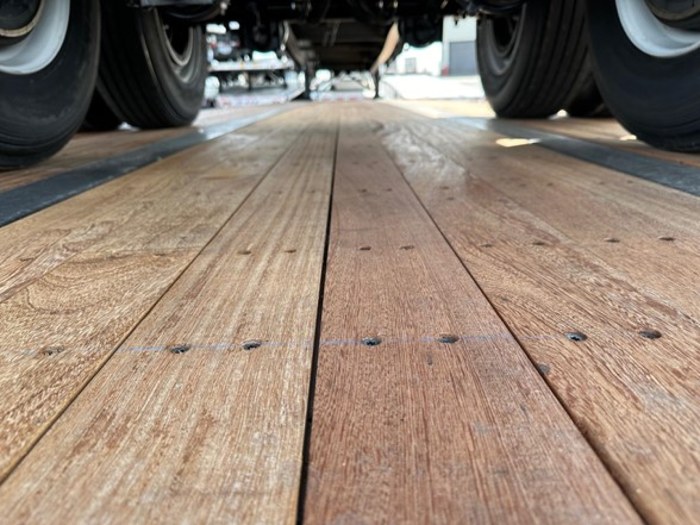 Utility 4000S trailer viewed from ground level showing wooden deck planks with fasteners and dual rear wheels.