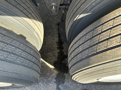 Flatbed trailer tires and suspension area showing dual axles and tires with tread pattern visible.