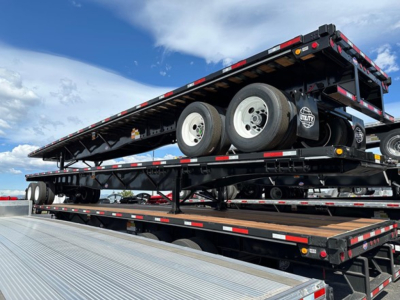 Utility 4000S flatbed trailer on a multi-axle lowbed, side view showing dual rear axles and spare wheel on deck.