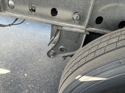 Trailer undercarriage showing mounting bracket and a wheel with tire tread, part of a Utility 4000S flatbed trailer.