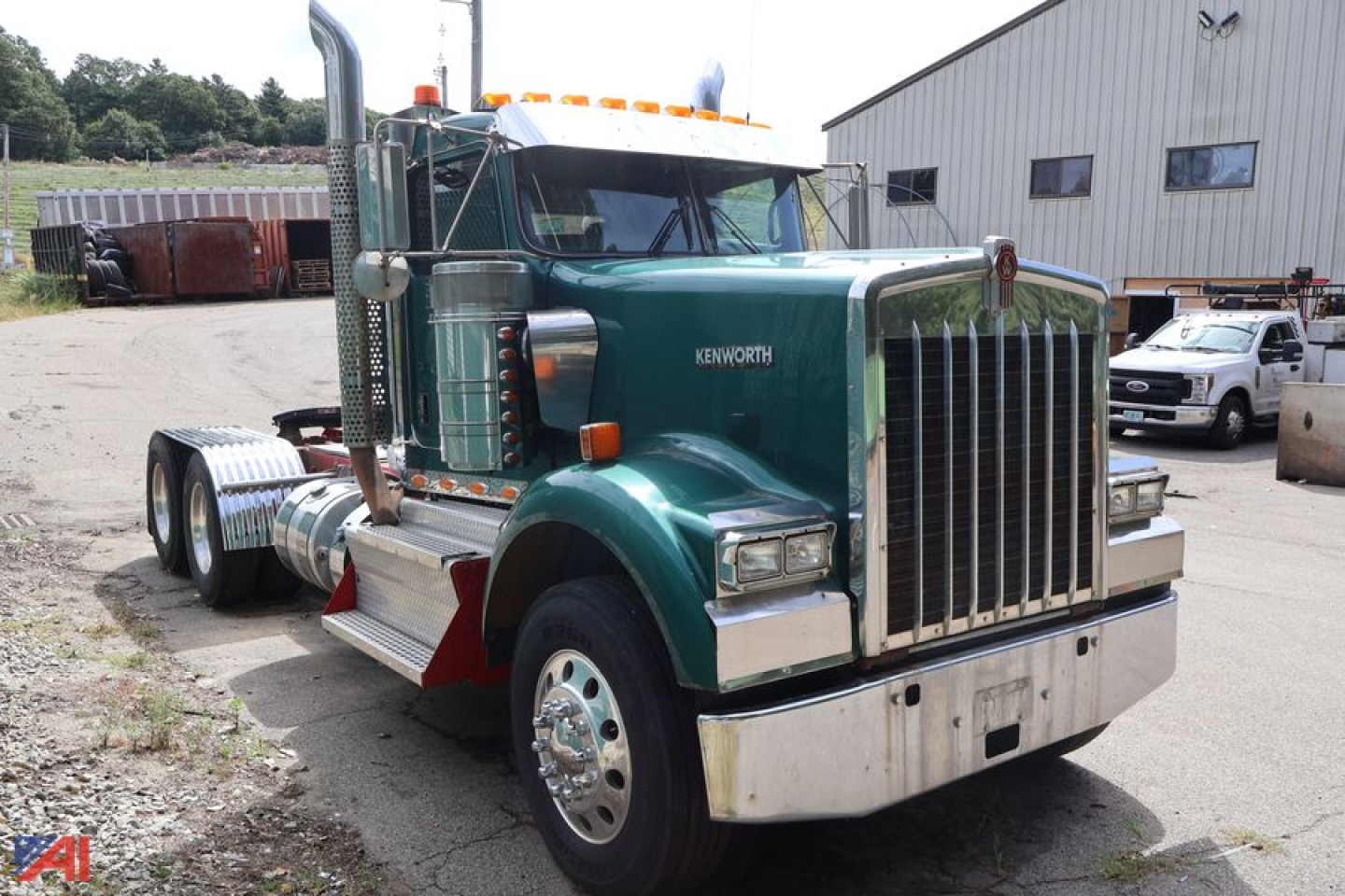 Kenworth W900 truck tractor side/front view showing green cab, chrome grille, tall exhaust stacks, dual rear axles, and fuel tanks.