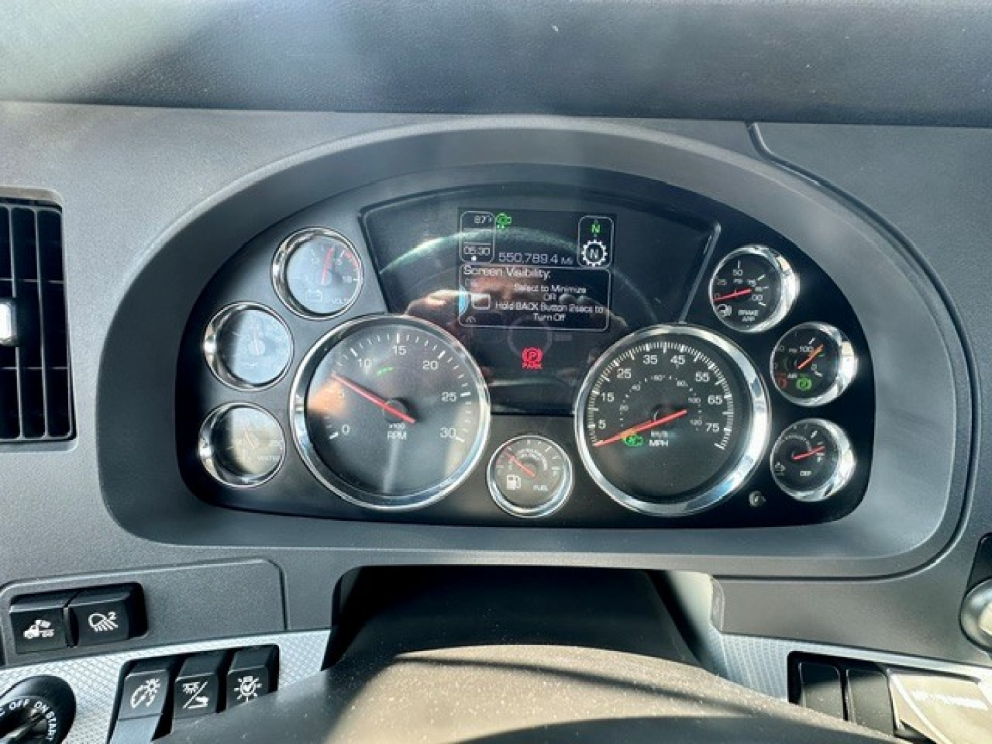 Kenworth T680 dash cluster showing multiple gauges and a central digital display.