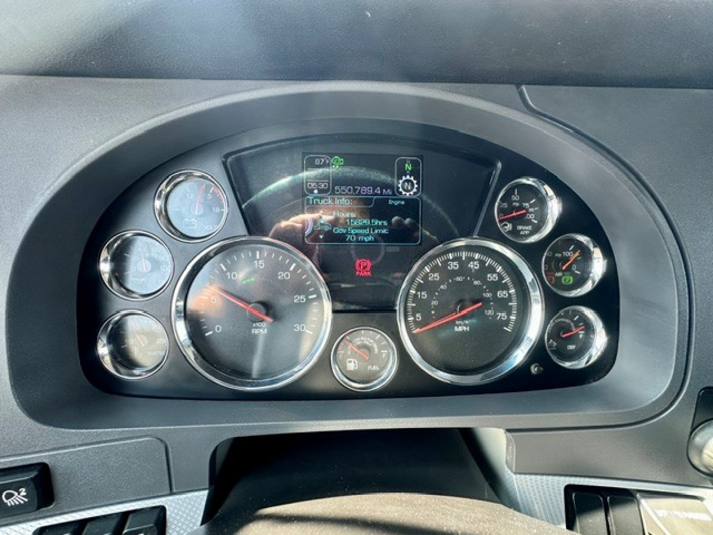 Kenworth T680 dashboard showing multiple gauges and digital display in center with speedometer and tachometer visible.