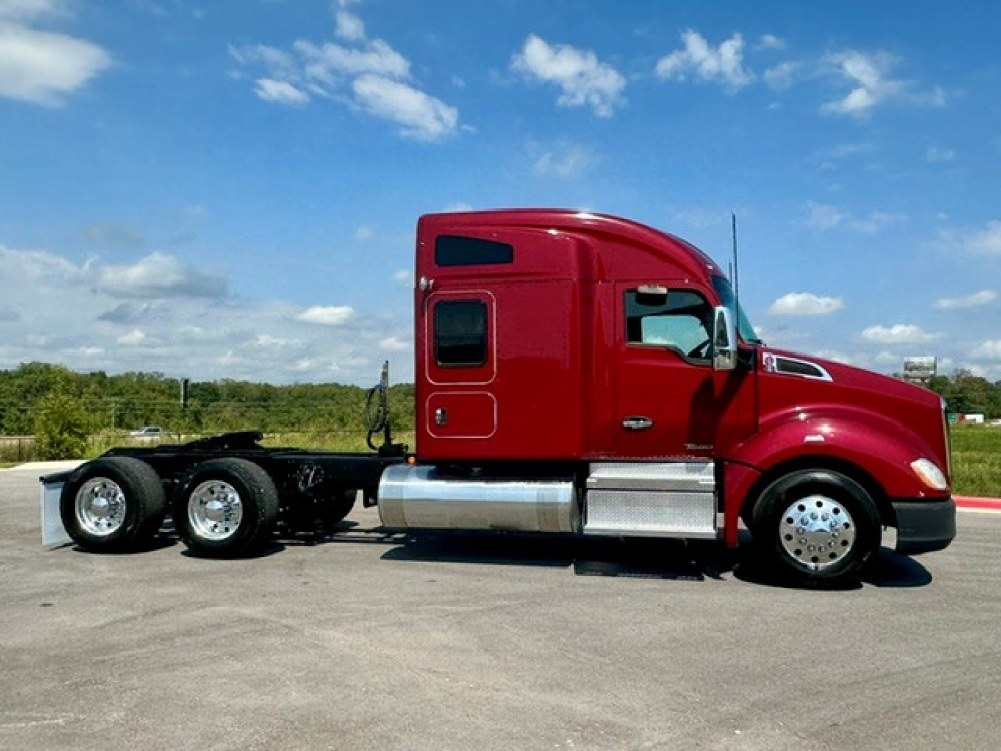 Kenworth T680 tractor in red, side view, single-row sleeper, 6-wheel tandem chassis, chrome fuel tank and steps visible.
