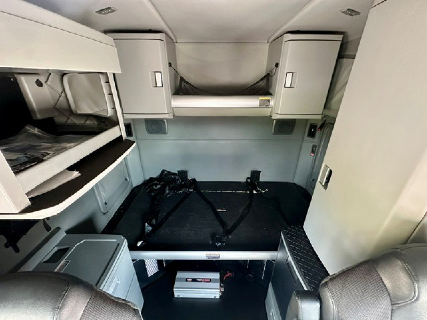Kenworth T680 sleeper cab interior with bunk bed area, storage cabinets, and ladder steps visible.