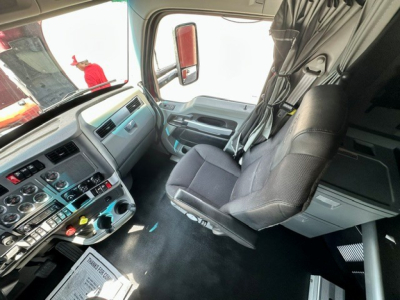 Kenworth T680 cab interior view with steering wheel, dashboard controls, and driver's seat; appears from doorway angle.