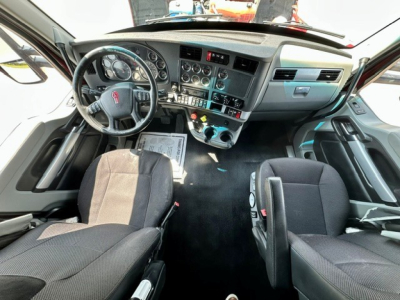Kenworth T680 interior view showing steering wheel, dashboard gauges, and center console with multiple switches in the cab.