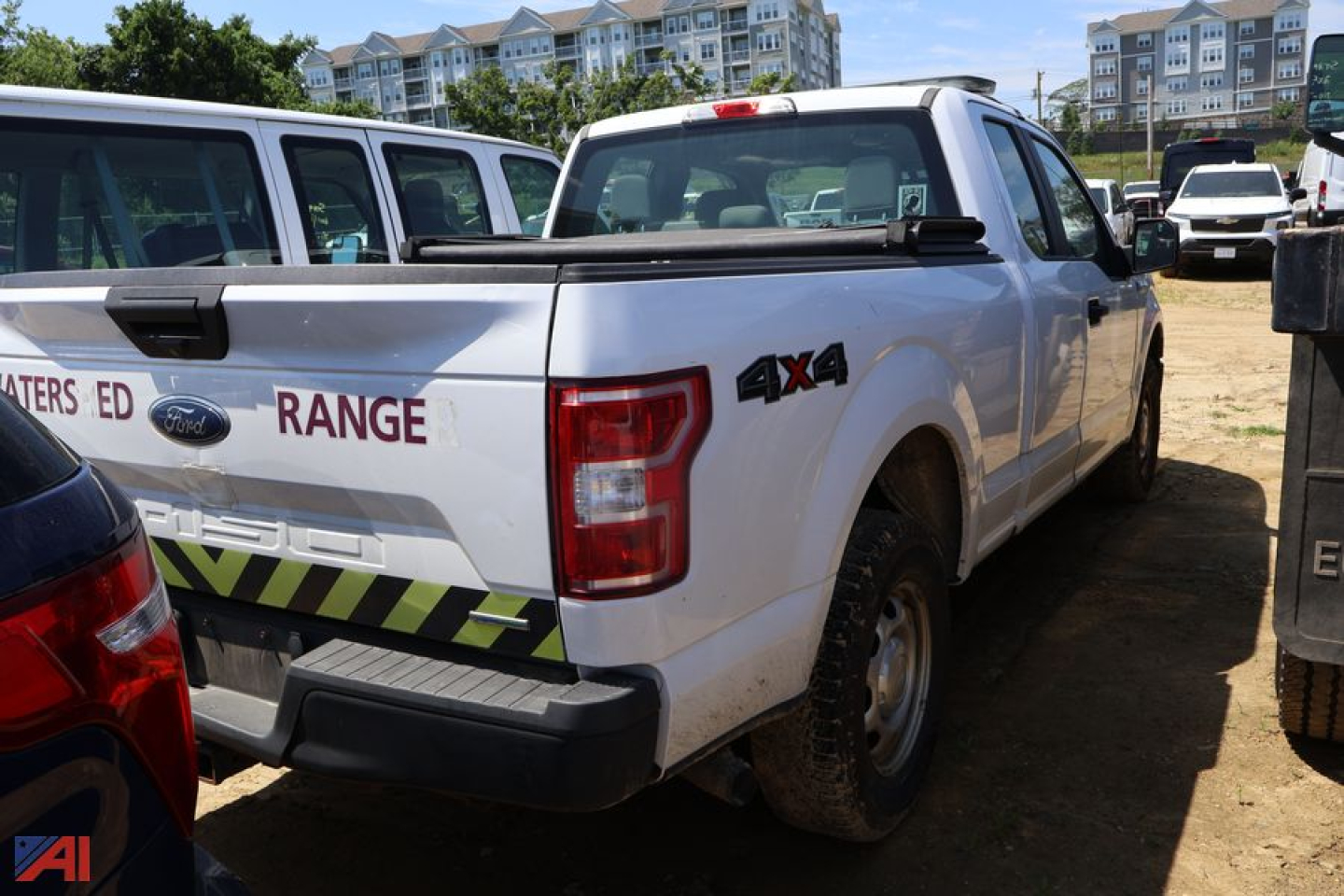 Ford F-150 pickup truck rear and side view showing 4x4 badge and Ranger misspelling on tailgate, white cab, in a dealership lot.