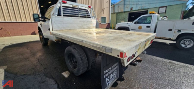 Flatbed utility truck rear angle showing dual rear wheels with flatbed and tail lights.