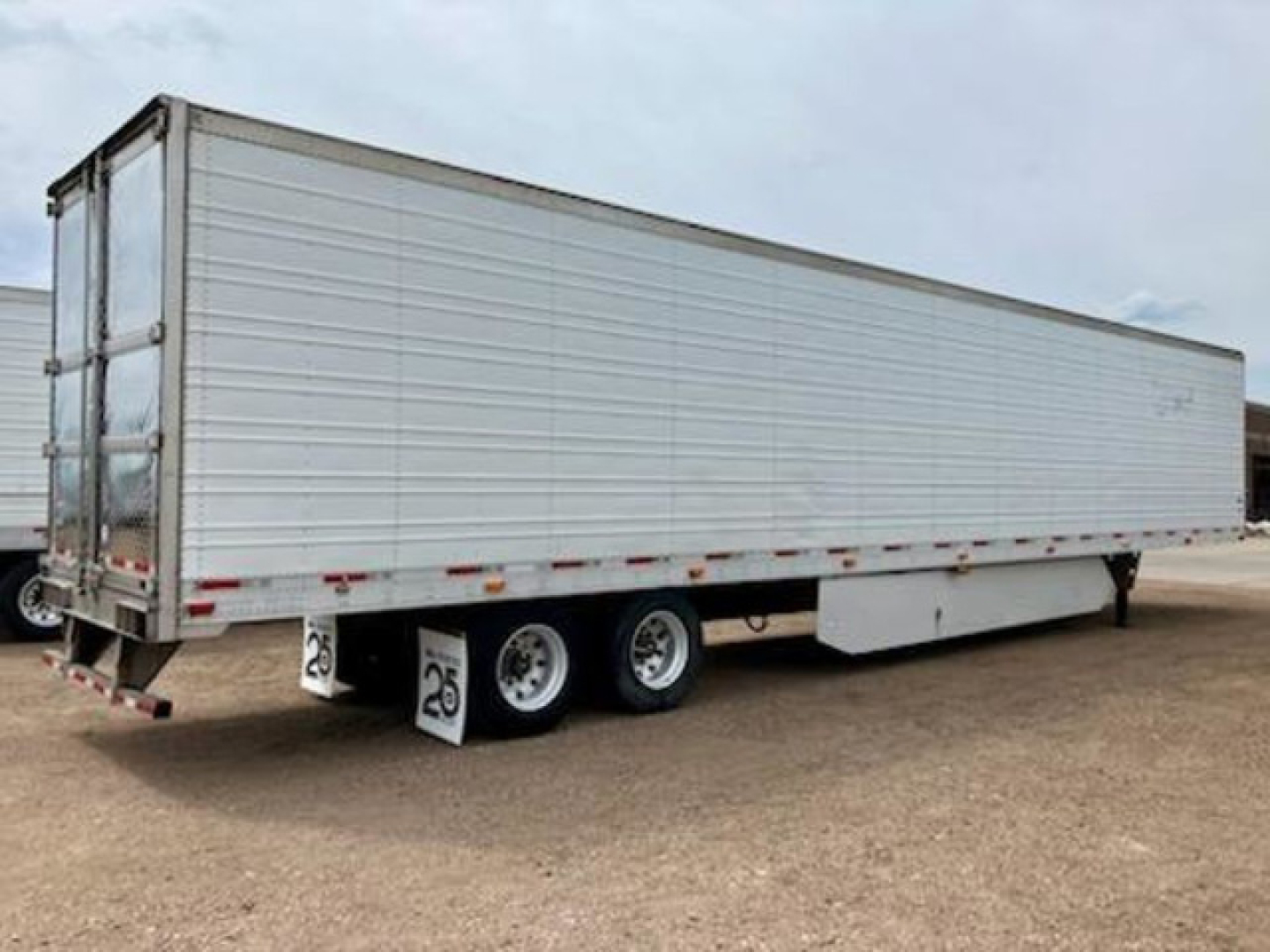 2017 Utility Reefer trailer showing side and rear wheels. Text visible includes '25' on mudflaps near rear, and reflective tape along lower edge. Exterior is silver metal paneling with doors at rear.