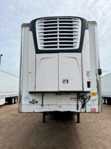Refrigerated trailer front view showing cooling unit and hitch area under a clear sky.