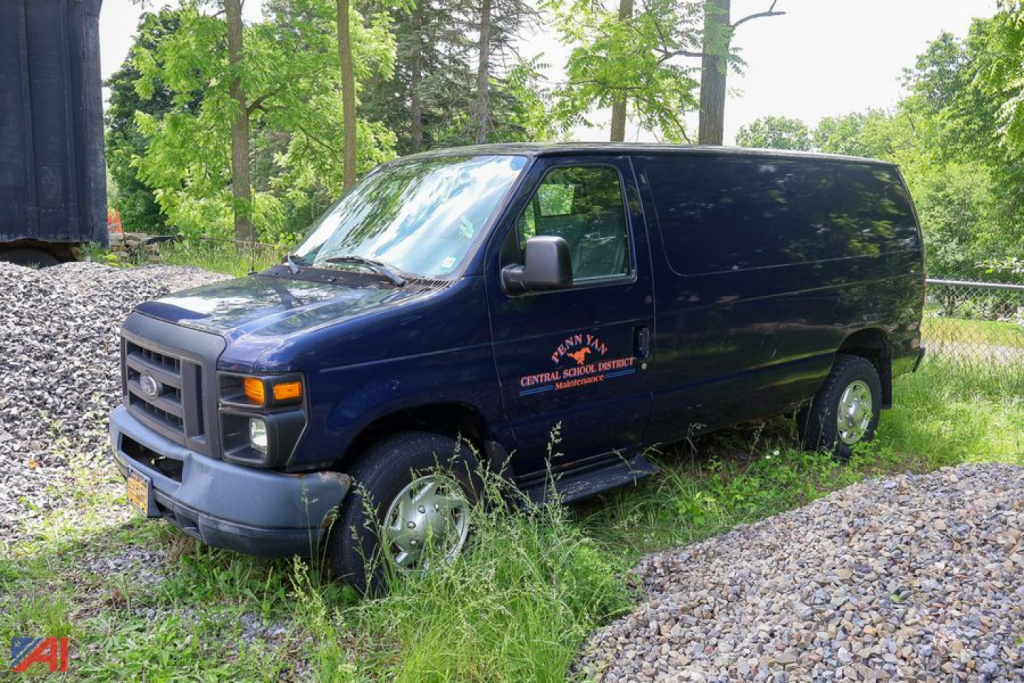 Ford E-250 cargo van in blue, side view showing front grille and wheel, used vehicle.