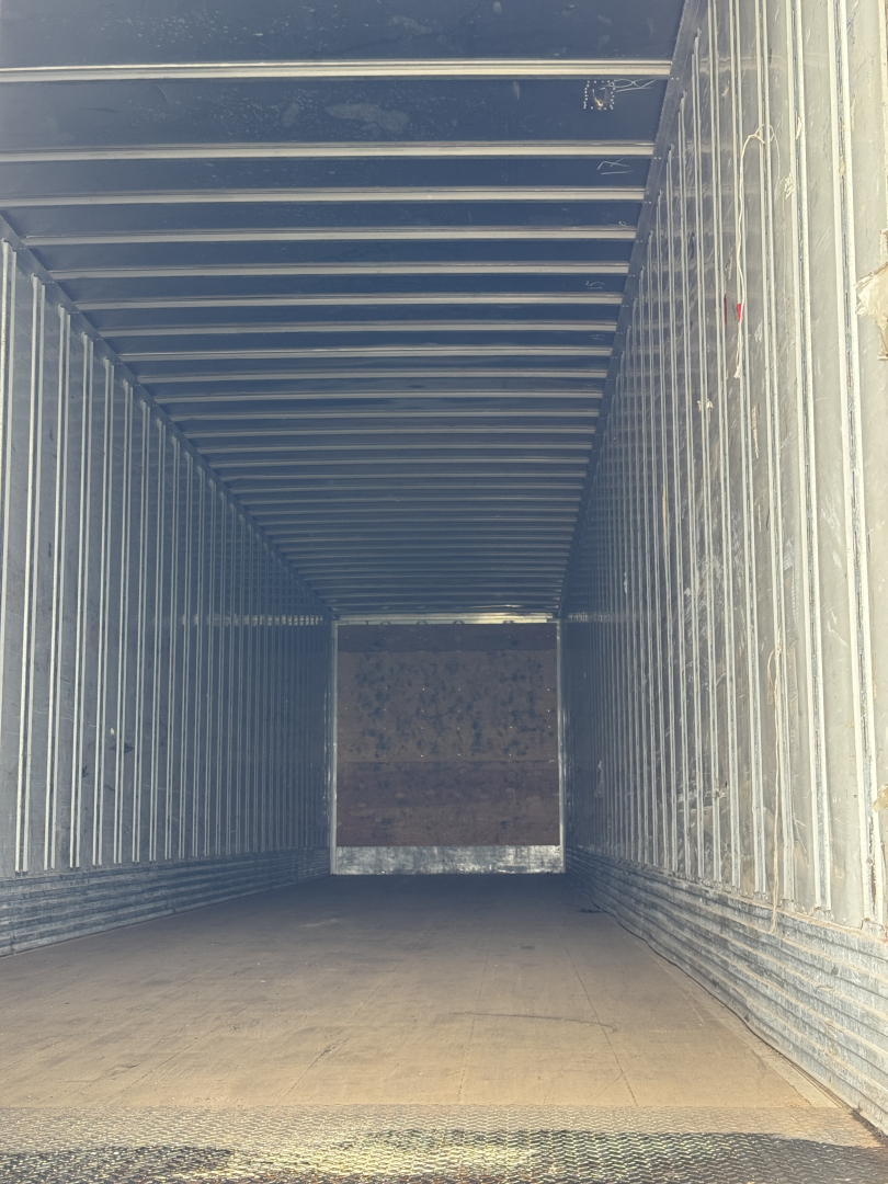 Trailer interior showing empty cargo space with metal walls and ceiling, wooden floor, rear light entry, for 2014 Utility 4000D-X.