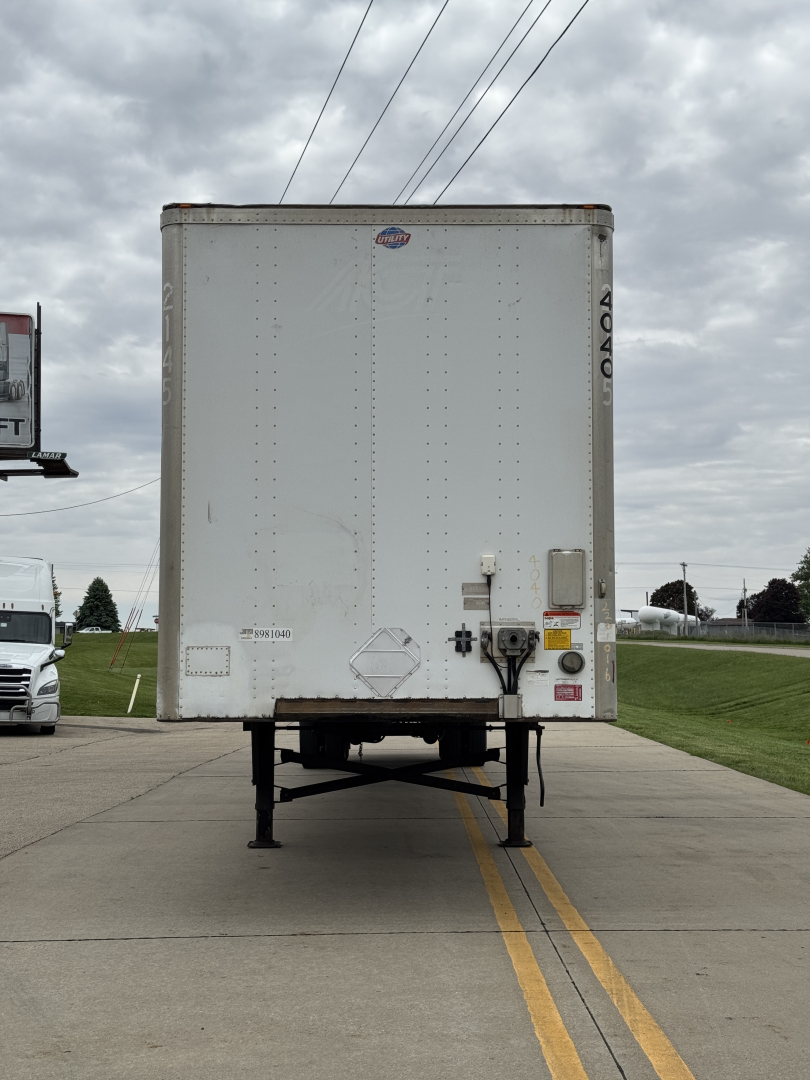 Rear view of a 2014 Utility 4000D-X trailer showing back doors, support legs, and bumper with VIN label and stickers.