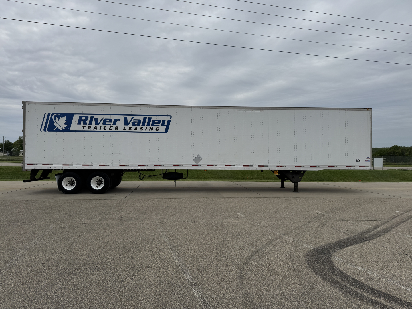 Long white trailer with River Valley Trailer Leasing logo on blue graphic, tandem axles at back, parked on lot.