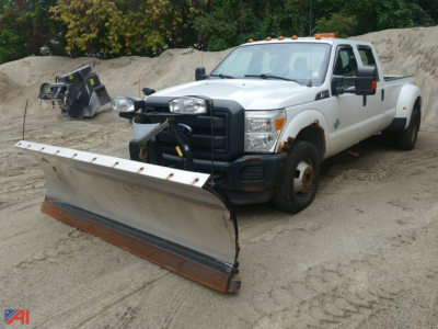 Ford F-350 Super Duty crew cab pickup with a front plow attached, white crew cab 4x4, large service bed, dirt lot backdrop.