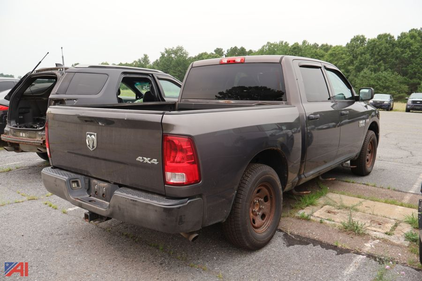 Truck bed view of a dark gray 2014 Ram 1500 Crew Cab 4x4 pickup with rear taillights, back window, and rust-colored wheels.