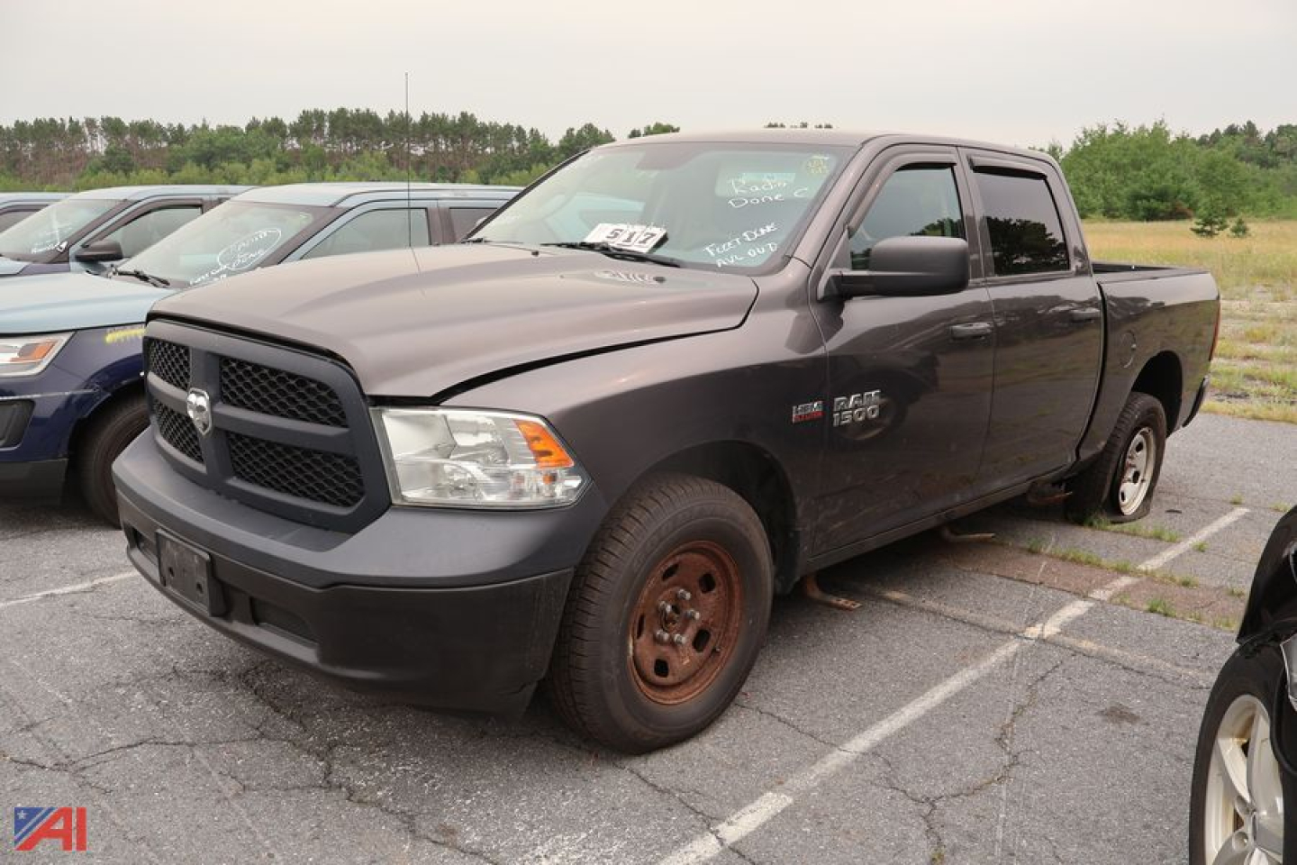 Ram 1500 pickup truck in a parking lot, front-left view, dark gray, crew cab, with single rear wheel on visible side.