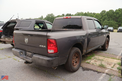 Truck bed view of a dark gray 2014 Ram 1500 Crew Cab 4x4 pickup with rear taillights, back window, and rust-colored wheels.