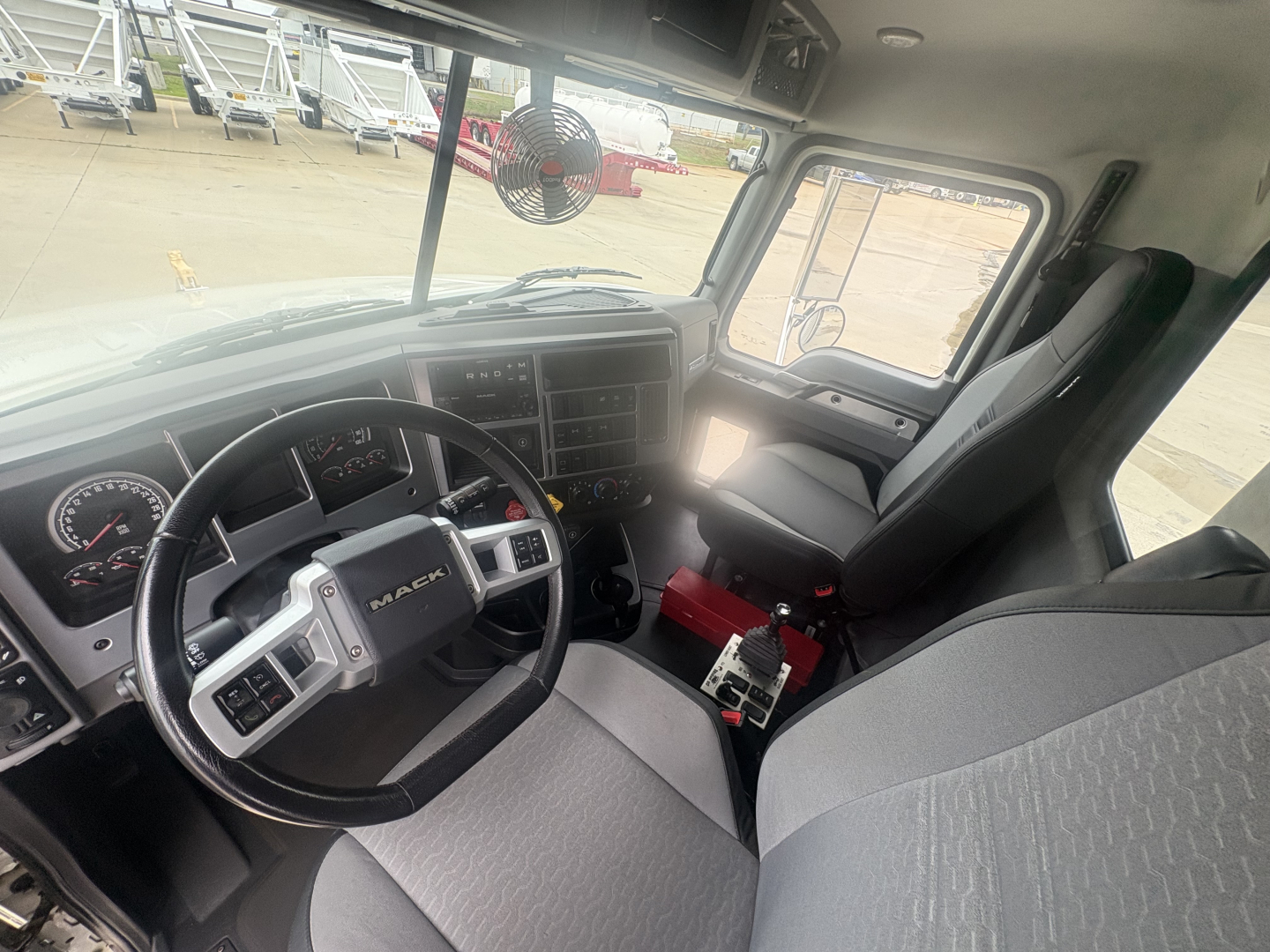 Mack GR64F truck cab interior showing steering wheel, dash, seats, and controls.