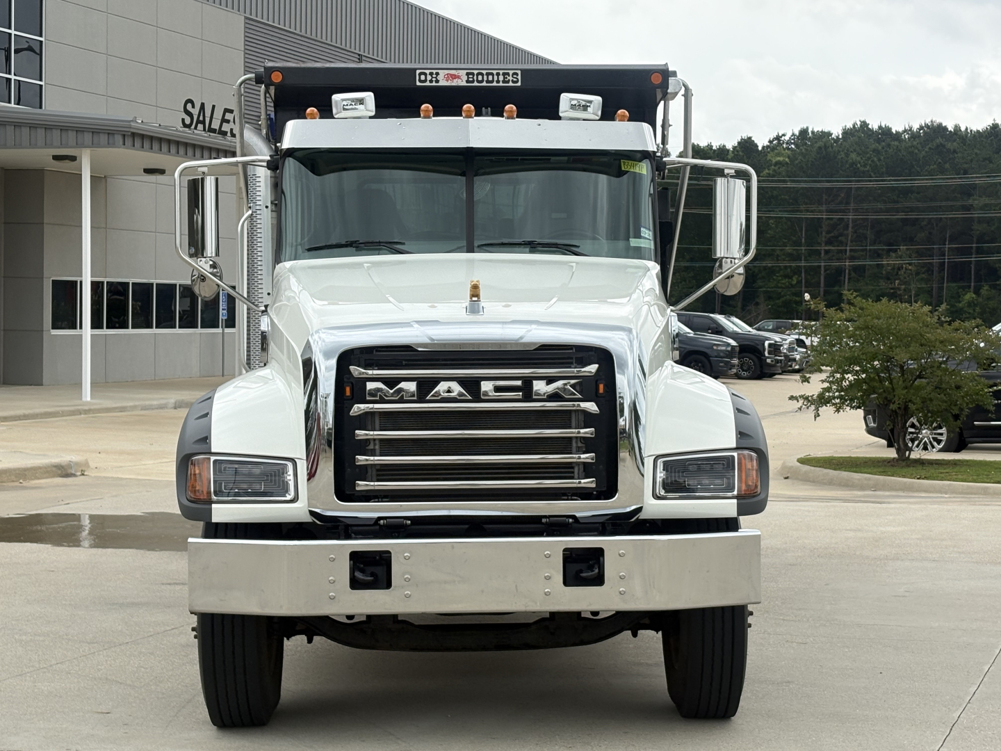 Mack GR64F dump truck front view showing Mack grille, bumper, headlights, and chrome mirrors.