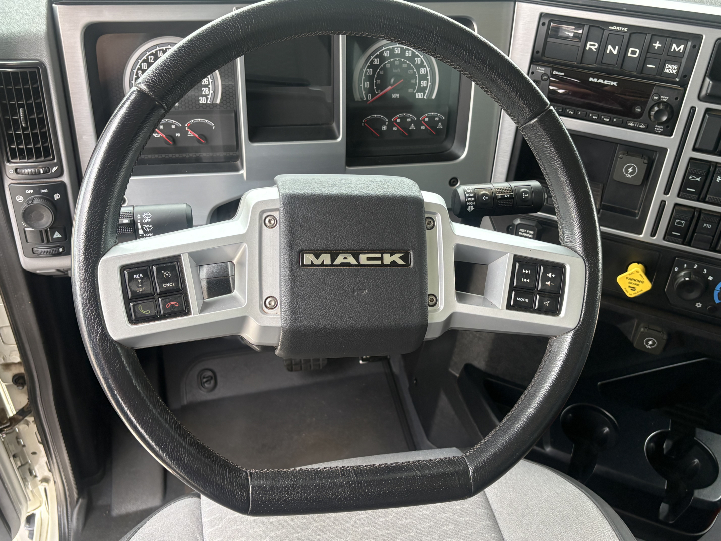 Mack GR64F steering wheel and dash showing instrument cluster and controls.