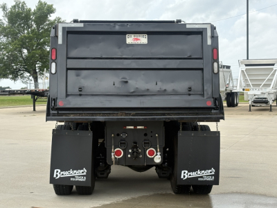 Rear view of a 2025 Mack GR64F dump truck showing rear bumper, taillights, license plate area, and mud flaps with Bruckner's branding.