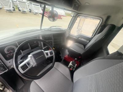 Mack GR64F truck cab interior showing steering wheel, dash, seats, and controls.