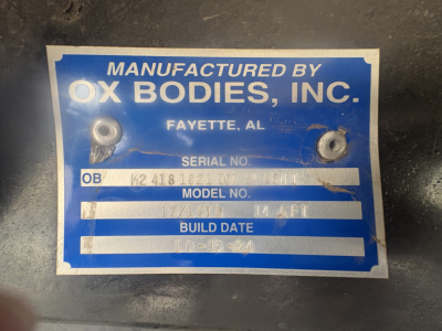 Manufactured by Ox Bodies, Inc. plate with serial/ob and model information on a blue label. Text shows 'MANUFACTURED BY OX BODIES, INC. FAYETTE, AL' with serial number fields and 'MODEL NO.' and 'BUILD DATE' visible.