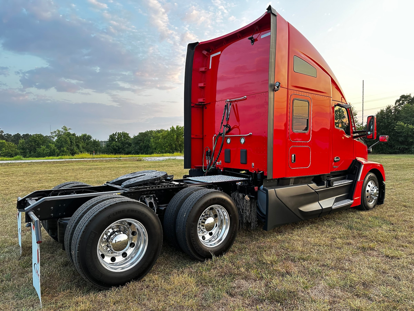 Kenworth T680 truck chassis and cab in red, side view showing sleeper cab, rear wheels, and fuel/tank area with access panels.