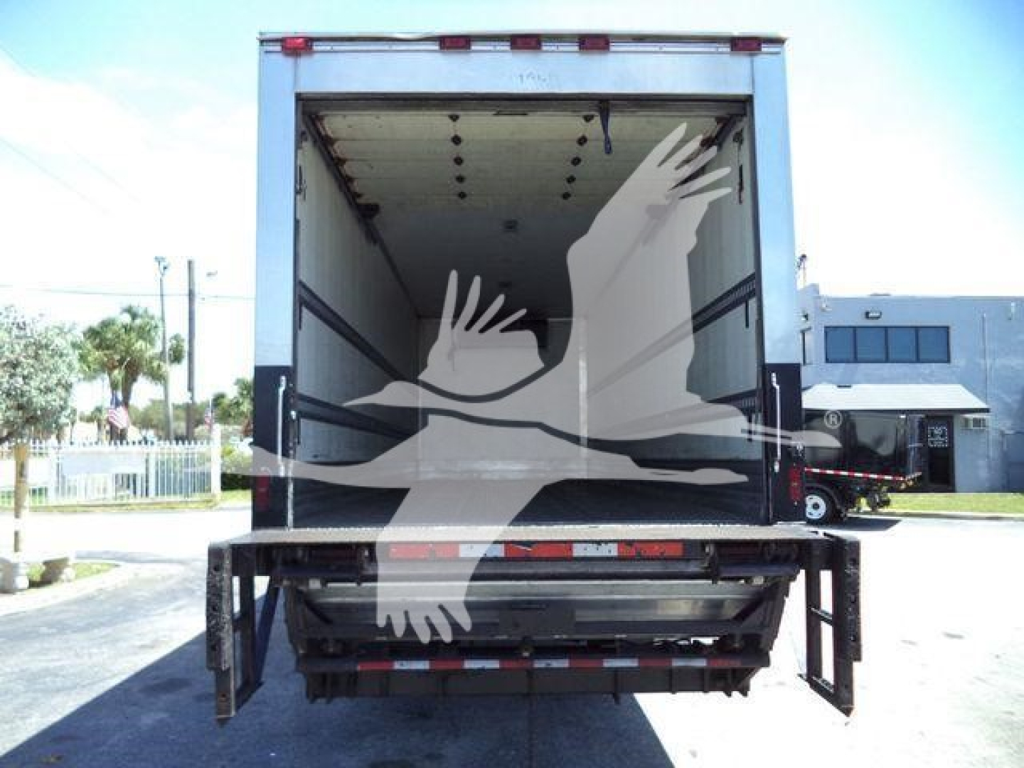 Refrigerated truck with open rear doors showing cargo area of a 2019 Hino 268A in a yard.
